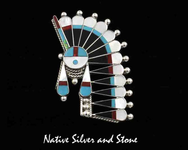 Z Fabian Cellicion- Zuni<br>Pendant/Pin - Inlaid<br>Large Sunface with Offset Headdress<br>Turquoise, White Mother of Pearl, Coral, and Jet<br>w Sterling Silver Accent